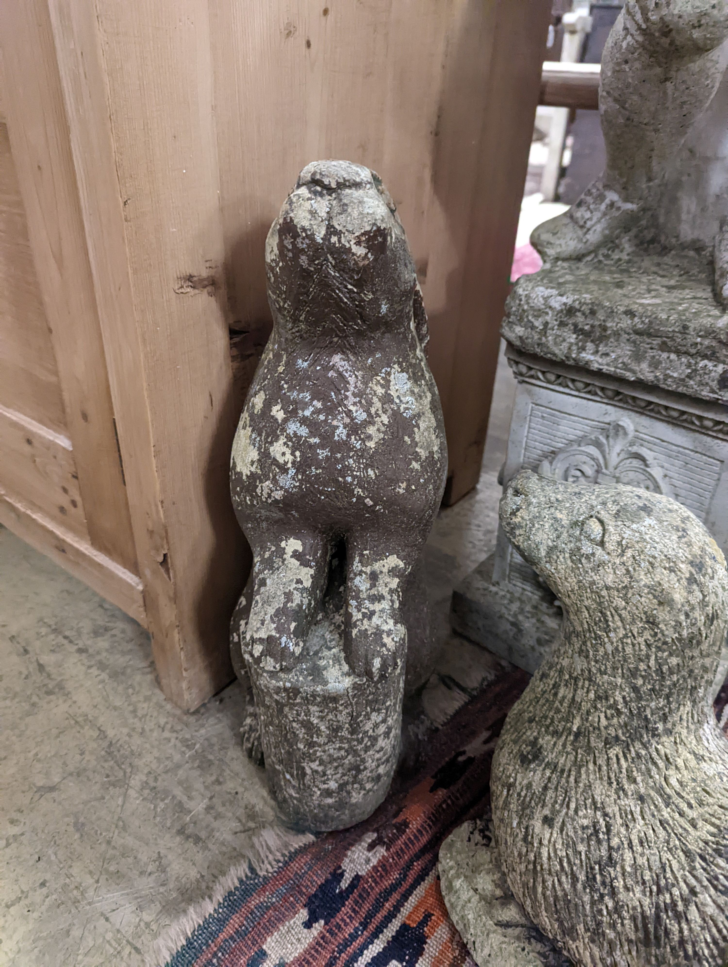 Four reconstituted stone garden ornaments modelled as a flower seller, height 102cm, hare, seal and eagle